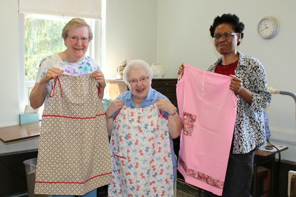 One of Sister Lupe's favorite opportunities was when Sister Esther Okwor (far right) returned to Nigeria taking with her pillowcase dresses for little girls made by Sister Ann Hehl (far left) and herself.