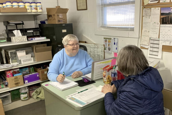 Sr. Marie Carla assisting a client sign in while volunteering at the St. Vincent de Paul food pantry.