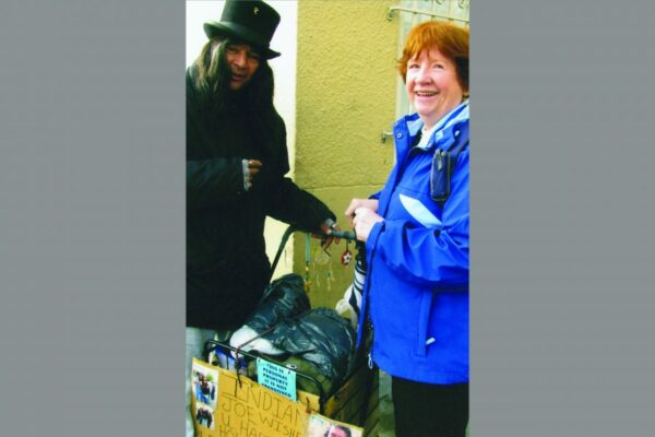 Sister Irene Mary McDonnell is pictured with Indian Jo, one of 2,500 people who are homeless that will stand in line waiting for a hot meal at St. Anthony’s in the Tenderloin District of San Francisco. Indian Joe daily greets people who pass by. His cart, partially seen here, contains all his possessions.